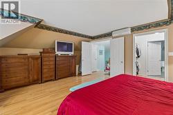 Sloped ceiling design, light wood-finish flooring, white double doors, and a wall-mounted climate control unit - 