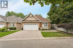 Brick exterior with stone accents, a two-car garage, and a paver driveway - 