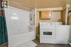 Full-size appliances, built-in cabinetry, and a bathtub with tile surround - 