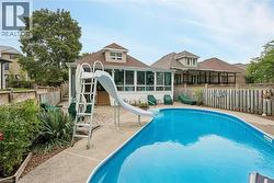 Curved inground pool with concrete surround, screened-in porch, and a raised wood deck - 