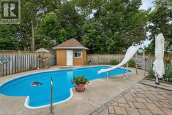 In-ground swimming pool with a white slide, concrete surround, and adjacent stone paver patio - 