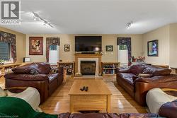 Hardwood flooring throughout, a central fireplace with a wood mantle, and track lighting - 