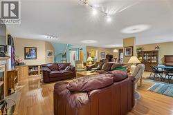 Open-concept living space featuring wood-finish flooring, a built-in media cabinet, and track lighting - 