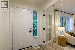 Paneled entry door with sidelight, interior paneled door with glass inserts, recessed lighting, and wood-finish flooring - 