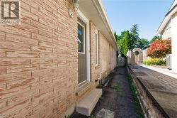 Brick exterior with a side entry door, concrete steps, and a paved walkway - 