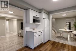 White cabinetry with dark hardware, subway tile backsplash, and light-tone countertops - 