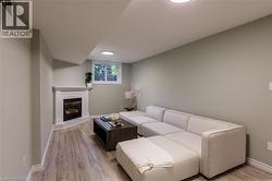 Recessed ceiling lighting, wood-finish flooring, corner fireplace with white mantel, and single window with white shutters - 