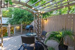 Wood-finish deck with a pergola, exterior privacy fencing, and an attached outdoor light fixture - 