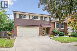 Brick and horizontal siding exterior with a two-car garage, concrete driveway, and mature landscaping - 