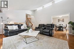 Vaulted ceilings with transom windows, wood-finish flooring, staircase with wood banister, and a distinct dining area - 