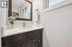 Dark wood-finish vanity with paneling, white countertop, undermount sink, and brushed nickel faucet - 