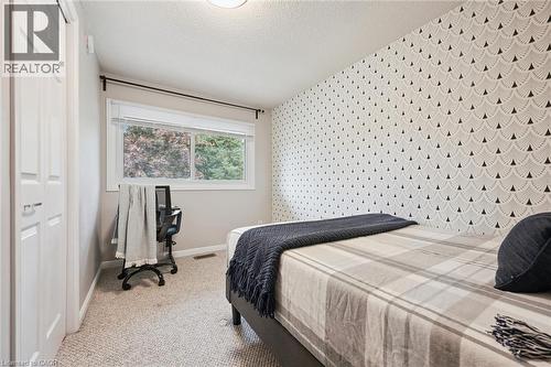 Textured accent wall, neutral carpeting, white trim, and a window with natural light - 21 Colebrook Court, Kitchener, ON 