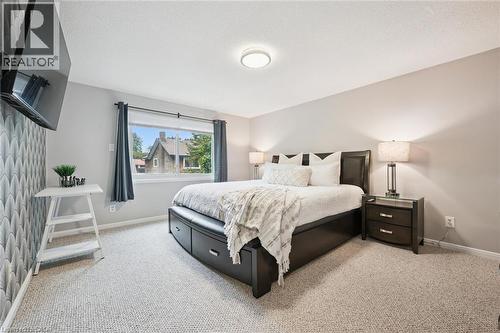 Carpeted flooring, recessed ceiling lighting, a window with roller shade, and an accent wall featuring patterned wallpaper - 21 Colebrook Court, Kitchener, ON 
