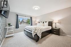 Carpeted flooring, recessed ceiling lighting, a window with roller shade, and an accent wall featuring patterned wallpaper - 