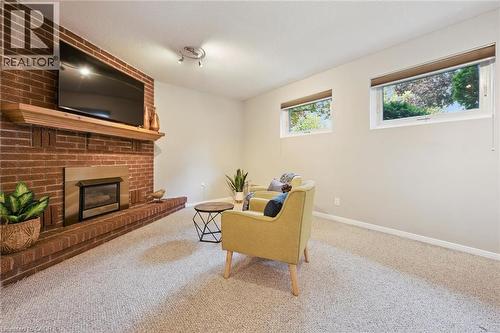 Brick-clad fireplace with a wood mantel, integrated firebox, and a hearth - 21 Colebrook Court, Kitchener, ON 
