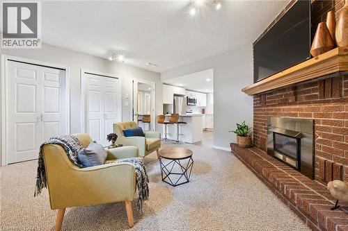 Brick fireplace with a wood mantle, carpeted flooring, and recessed lighting - 21 Colebrook Court, Kitchener, ON 