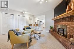 Brick fireplace with a wood mantle, carpeted flooring, and recessed lighting - 