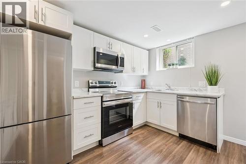 White shaker cabinetry, stainless steel appliances, light-toned countertops, wood-finish flooring, and recessed lighting - 21 Colebrook Court, Kitchener, ON 