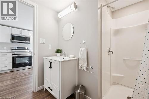 White vanity with a single basin sink, round wall mirror, and chrome fixtures - 21 Colebrook Court, Kitchener, ON 