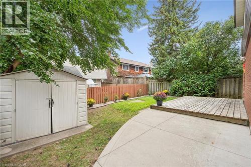Fenced backyard featuring a concrete patio, wood deck, and a storage shed - 21 Colebrook Court, Kitchener, ON 