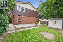 Brick and siding exterior with a wood deck, concrete walkway, and a storage shed - 