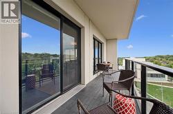 Expansive balcony featuring composite decking, glass panel railing, and a sliding glass door with dark trim - 