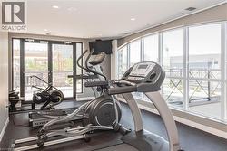 Fitness area featuring rubberized flooring, recessed lighting, expansive arched windows, and direct access to an outdoor patio - 
