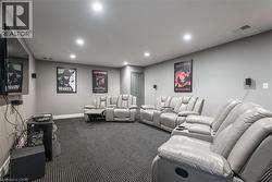 Dedicated media room featuring recessed lighting, wall-mounted speakers, and textured carpet flooring - 