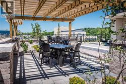 Expansive patio with a wooden pergola, paver flooring, stone accent walls, and landscaped garden beds - 