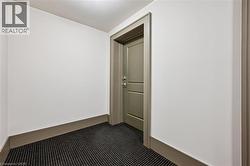 Recessed lighting illuminates a neutral wall color, dark patterned carpeting, and a framed doorway - 