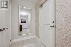 Floor-to-ceiling mirror with a silver-finish frame, light-toned patterned wallpaper, and light-toned floor tiling - 