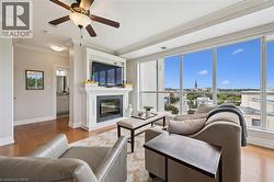 Living space with a built-in fireplace, extensive window wall, wood-finish flooring, and crown molding - 