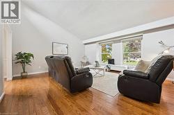 Vaulted ceiling with a neutral paint palette, wood-finish flooring, and large windows - 