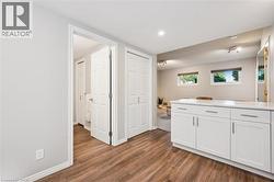 Wood-finish flooring, white cabinetry with a light-toned countertop, recessed lighting, and track lighting fixtures - 