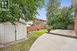 Fenced backyard featuring a concrete patio, wood deck, and a storage shed - 
