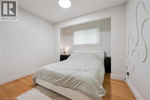 Bright room featuring wood-finish flooring, a built-in architectural wall niche, a single window with blinds, and a flush-mount ceiling light fixture - 135 Bridge Street W, Waterloo, ON 