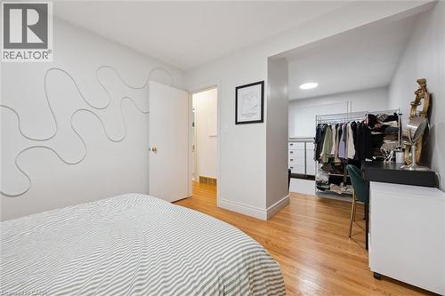 Bedroom featuring wood-finish flooring and an open doorway to a walk-in closet with a visible skylight - 135 Bridge Street W, Waterloo, ON 