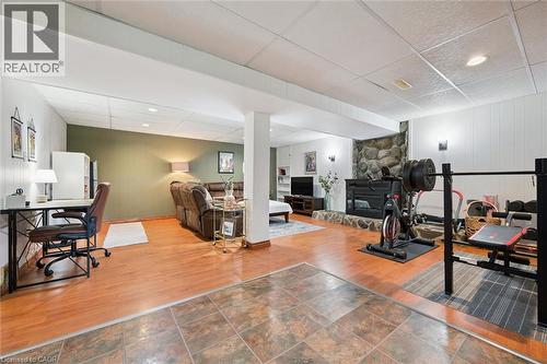 Lower level featuring distinct activity zones, a stone fireplace, wood-finish flooring, recessed lighting, and wall sconces - 135 Bridge Street W, Waterloo, ON 