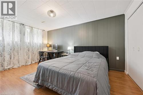 Room featuring wood-finish flooring, a paneled accent wall, and a built-in closet with bifold doors - 135 Bridge Street W, Waterloo, ON 