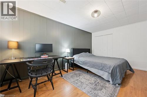 Interior room featuring wood-finish flooring, two-tone wall paneling, and a white grid ceiling - 135 Bridge Street W, Waterloo, ON 