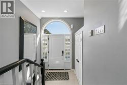 Arched transom window above a paneled entry door with sidelights, featuring white plantation shutters - 