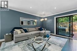 Recessed lighting illuminates the room, featuring wood-finish flooring and crown molding - 