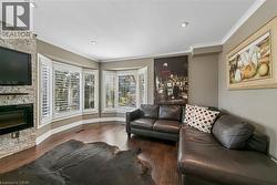Hardwood flooring, recessed lighting, crown molding, stone fireplace, and bay window with plantation shutters - 