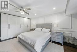 Full-wall built-in wardrobes, ceiling fan with integrated lighting, recessed ceiling lights, dark wood-finish flooring, and decorative wall molding - 