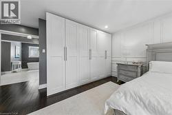 Full-height built-in wardrobes, dark wood-finish flooring, decorative wall molding, recessed ceiling lighting, and an adjacent bathroom with a freestanding tub - 