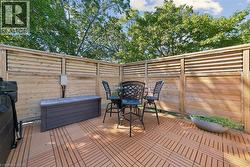 Private outdoor patio featuring slatted wood fencing, interlocking deck tiles, and mature perimeter trees - 