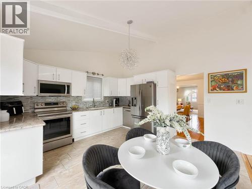 Kitchen featuring white cabinetry, stainless steel appliances, a multi-tone tile backsplash, and light-toned flooring - 1236 Thorpe Road, Burlington, ON 
