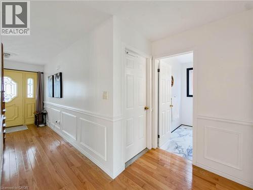 Hardwood flooring throughout, wainscoting paneling, transom windows, yellow front door with decorative glass, and white interior doors - 1236 Thorpe Road, Burlington, ON 