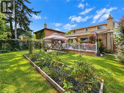 Expansive backyard featuring a large raised garden bed, manicured lawn, and mature perimeter greenery - 1236 Thorpe Road, Burlington, ON 