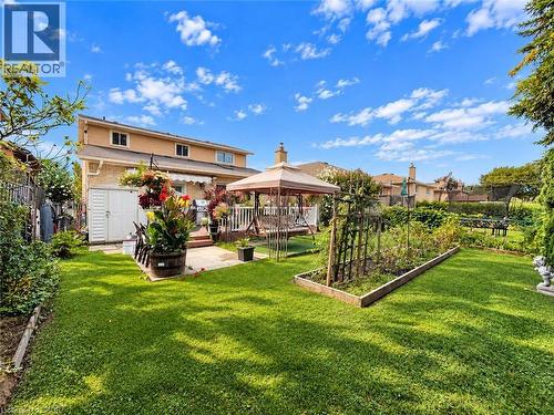 Expansive backyard featuring a manicured lawn, a raised garden bed, a paved patio, and a utility shed - 1236 Thorpe Road, Burlington, ON 